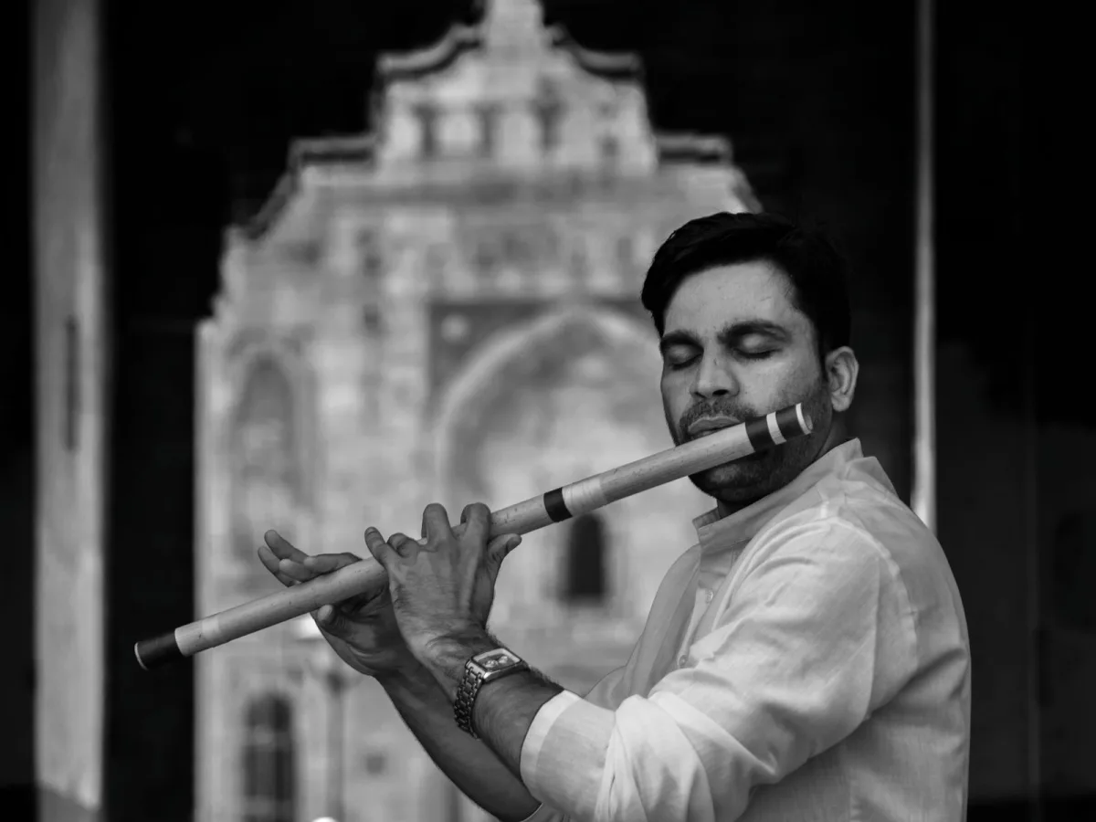 Black-and-white portrait of a flautist playing the bansuri with his eyes closed
