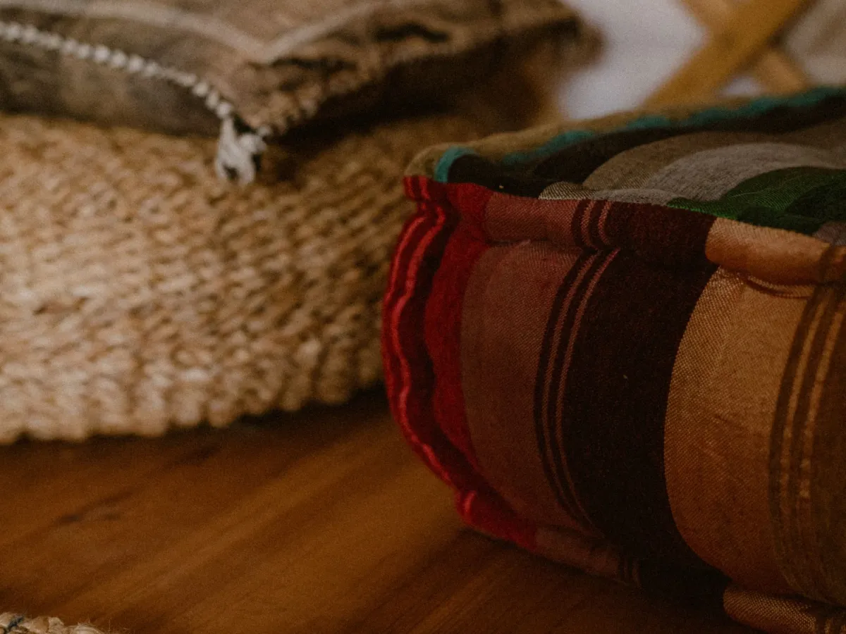 Striped floor cushions and a woven rug laid out on a wooden floor before an evening